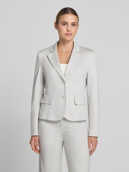 Frauenmodel trägt Slim Fit Blazer mit Pattentaschen von Marc Cain aus Material-Mix mit Baumwoll-Anteil, Reverskragen, Knopfverschluss, Ganzkörperansicht von vorne.