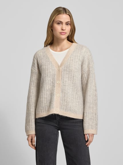 Frauenmodel trägt Relaxed Fit Strickpullover aus Woll-Mix mit Alpaka-Anteil Modell 'FALVA' von Selected Femme, beige-grau, Strukturmuster, Knopfleiste, gerippte Abschlüsse, Allover-Muster, Ganzkörperansicht von vorne.