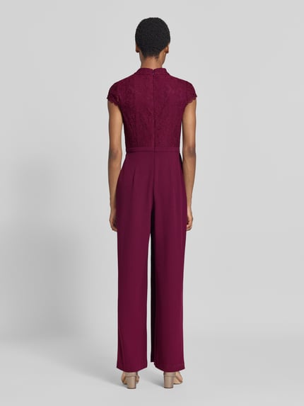 Männermodel trägt Regular Fit Jumpsuit mit Ozdobna kokarda od Adrianna Papell, Mieszanka materiałów z dodatkiem wiskozy, krój regular fit, obszycie koronką w kwiatowy wzór, z krótkim rękawem, długość tyłu w rozmiarze 36: 37 cm, szerokość w rozmiarze 36: 40 cm, całkowita długość w rozmiarze 36: 150 cm, długość wewnętrzna nogawki w rozmiarze 36: 84 cm, widok całej sylwetki z tyłu