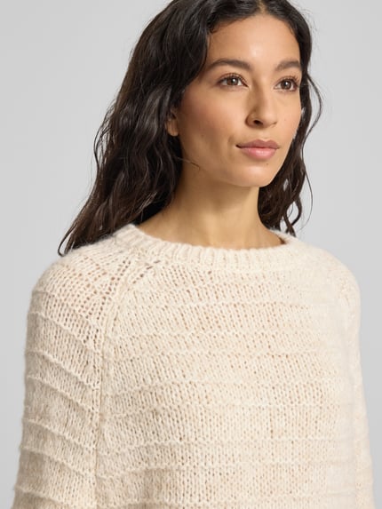 Modelka kobieca ma na sobie Strickpullover mit Strukturmuster und Rundhalsausschnitt od Smith and Soul, kremowy sweter z fakturą, mieszanka z alpaki, regularny krój, widok z przodu, zbliżenie na górną część ciała.