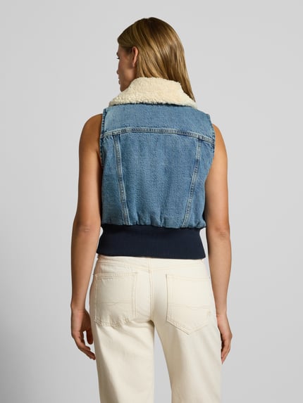 Kobieta modelka nosi Regular Fit kamizelkę z czystej bawełny model 'TINY SHERPA VEST' od Levi's®, kolor niebieski, tekstura jeansu, damska kamizelka, widok całej sylwetki od tyłu.