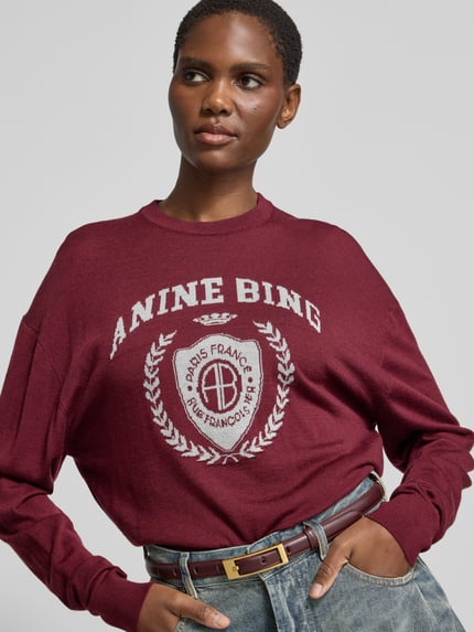 Frauenmodel trägt Sweatshirt mit Logo-Schriftzug Modell 'MIA SWEATER' von Anine Bing, bordeaux, Motiv-Print, Strick, Nahaufnahme Oberkörper.