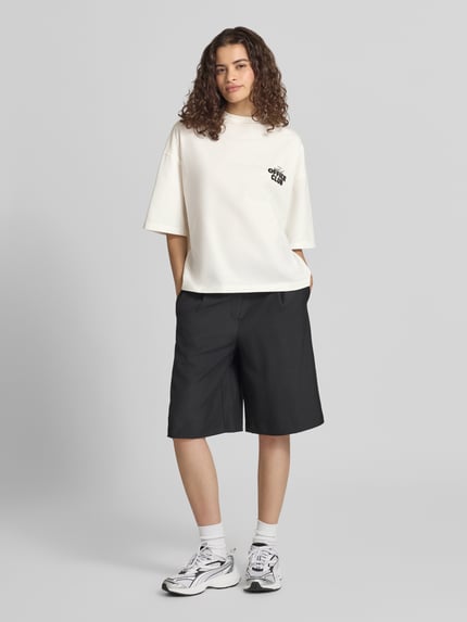 Frauenmodel trägt Cropped Oversized T-Shirt mit Label-Print von Karo Kauer in Weiß, reine Baumwolle, oversized, Ganzkörperansicht von vorne.