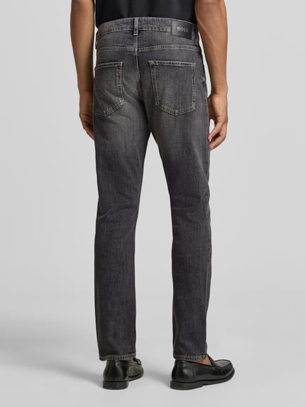 Männermodel trägt Slim Fit Jeans aus Stretch-Denim Modell 'DELAWARE' von BOSS in grauer Denim-Optik, 5-Pocket-Design, Ganzkörperansicht Rückansicht