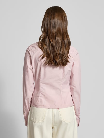 Frauenmodel trägt Slim Fit Hemdbluse aus reiner Baumwolle von Guess Jeans in Hellrosa, taillierte Passform, Ganzkörperansicht Rückansicht.