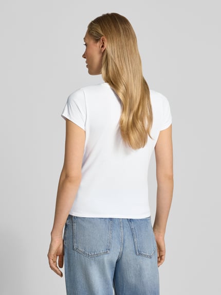 Frauenmodel trägt T-Shirt mit Label-Detail Modell 'LEOPARDTINI' von Guess in Weiß, körpernaher Schnitt, Rundhalsausschnitt, Baumwoll-Elasthan-Mix, Ganzkörperansicht Rückansicht.
