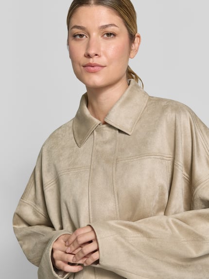 Frauenmodel trägt Relaxed Fit Blouson in Leder-Optik von COMMA in Beige mit Umlegekragen und Drapierungen, Nahaufnahme Oberkörper. Rückenlänge 52 cm, Brustweite 82 cm, Ärmellänge 45 cm.