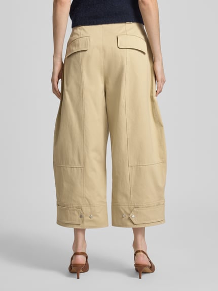 Frauenmodel trägt Loose Fit Chino aus reiner Baumwolle Modell 'Tikkara' von BOSS in Optik: Unifarben, Twill-Struktur, High-Waist, Gesäßpattentaschen, Weitenregulierung am Beinabschluss, Ganzkörperansicht Rückansicht.