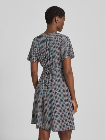 Männermodel trägt Knielanges Kleid aus Viskose mit V-Ausschnitt von zero, taliowany krój, Długość do kolan, Dekolt w serek, listwa guzikowa, wiązany pasek, Długość tyłu w rozmiarze 36: 90 cm, Szerokość w rozmiarze 36: 32 cm, Długość rękawów w rozmiarze 36: 21 cm, wielokolorowy wzór, tekstura miękka, Ganzkörperansicht Rückansicht.