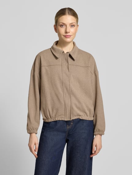 Frauenmodel trägt Regular Fit Jacke mit verdecktem Reißverschluss Modell 'Cl44aire' von ZABAIONE in Beige, glatte Struktur, Ganzkörperansicht von vorne. Rückenlänge 54 cm, Schulterbreite 62 cm, Brustweite 59 cm, Ärmellänge 48 cm.