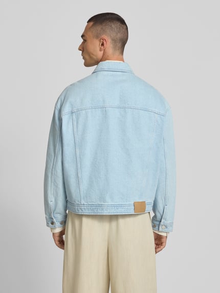 Männermodel trägt Jeansjacke aus reiner Baumwolle von MAISON KITSUNÉ in Hellblau mit Umlegekragen, gerade Passform, Rückansicht.