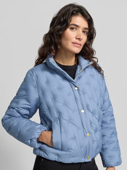 Frauenmodel trägt Regular Fit Daunenjacke mit Logo-Stitching von Tommy Hilfiger in Hellblau, strukturierte Oberfläche, Nahaufnahme Oberkörper. Damen Daunenjacke von Tommy Hilfiger.