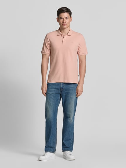 Męski model nosi Slim Fit Poloshirt mit Stitching von Jack & Jones Premium z bawełny, kolor jasnoróżowy, listwa guzikowa, krój slim fit, haft, długość tyłu w rozmiarze M: 70 cm, pełna sylwetka z przodu.