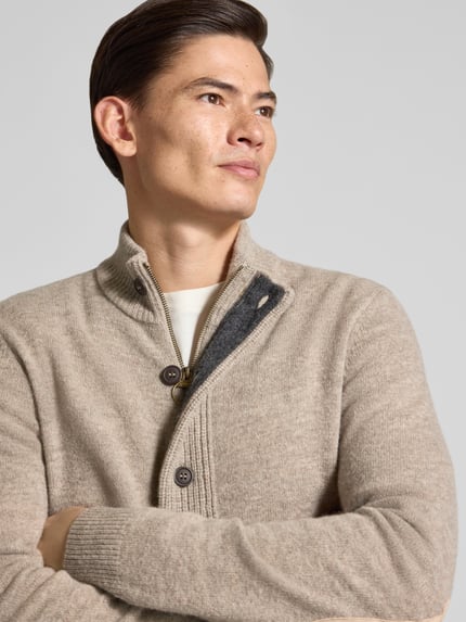 Männermodel trägt Cardigan mit Stehkragen Essential PATCH von BARBOUR in unifarbener Strickoptik mit durchgehender Knopfleiste, Nahaufnahme Oberkörper.