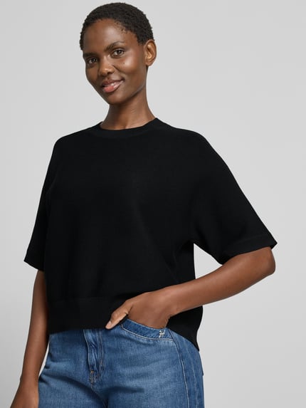 Frauenmodel trägt schwarzen Relaxed Fit Pullover aus Viskose-Mix Modell 'Thamira' von MSCH Copenhagen, Strick-Optik, Nahaufnahme Oberkörper.