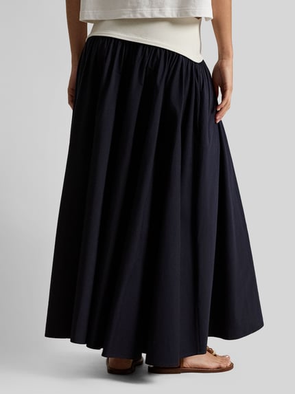 Vrouwenmodel draagt 'Ausgestellter Midi-Rock aus reiner Baumwolle' van Polo Ralph Lauren, two tone-look, uitlopend, logo-stiksel, lengte midi, detailopname rugaanzicht.