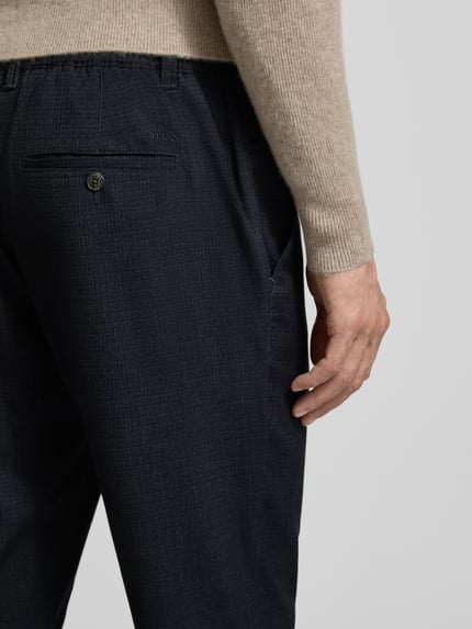 Männermodel trägt Stoffhose mit elastischem Bund von MCNEAL, dunkelblauer Material-Mix mit Viskose-Anteil, Detailaufnahme Rückansicht.