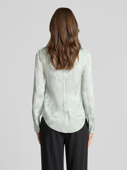 Frauenmodel trägt Bluse aus Viskose mit abgerundetem Saum von Calvin Klein Womenswear in hellem Grün, Kentkragen, Knopfleiste, Rückenlänge 65 cm, Ärmellänge 63 cm, Ganzkörperansicht Rückansicht.