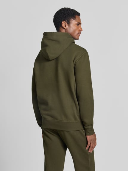 Męski model nosi Regular Fit Hoodie aus Baumwoll-Mix von Polo Ralph Lauren w kolorze oliwkowym, tekstura gładka, całkowity widok z tyłu.