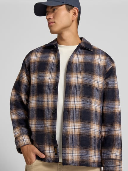 Männermodel trägt Regular Fit Hemdjacke mit Brusttasche Modell 'SOHO OLLIE' von JACK & JONES, kariert in Blau, Beige, Nahaufnahme Oberkörper. Herren Hemdjacke mit Kentkragen, durchgehender Knopfleiste, context-basiert.