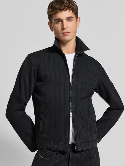 Männermodel trägt Slim Fit Jeansjacke aus Baumwoll-Mix von Diesel in Schwarz mit zamek błyskawiczny dwustronny, wykładany kołnierz, wpuszczane kieszenie, Długość tyłu w rozmiarze M: 64 cm, Szerokość ramion w rozmiarze M: 46 cm, Długość rękawów w rozmiarze M: 65 cm, strukturalna faktura, Ganzkörperansicht von vorne.