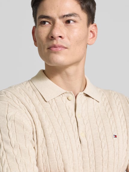 Männermodel trägt Regular Fit Strickpullover aus reiner Baumwolle von Tommy Hilfiger mit Zopfmuster, Optik: Unifarben, Nahaufnahme Oberkörper.