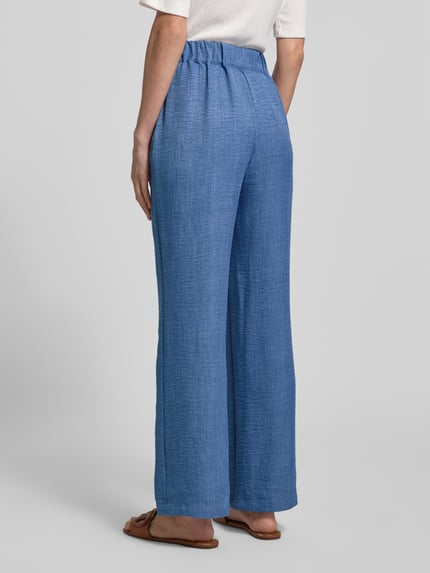 Frauenmodel trägt Hose in Denim-Optik Modell 'CHARISSA' von Soyaconcept, Wide-Leg-Design, elastischer Bund, Struktur, Ganzkörperansicht Rückansicht. Bundweite 36 cm, Innenbeinlänge 75 cm, Größe S.