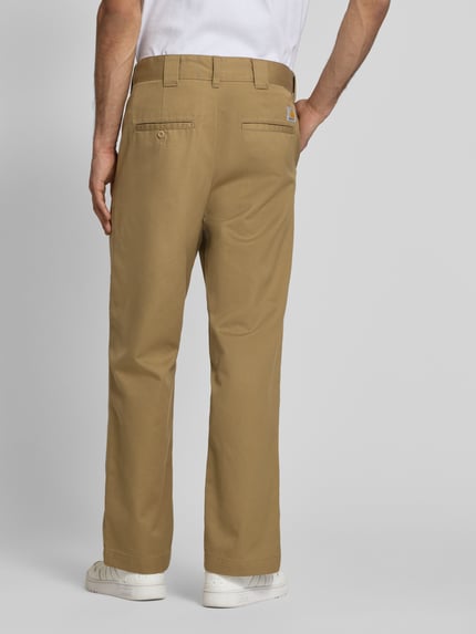 Mannenmodel draagt broek met achterzakken model 'Denison' van Carhartt Work In Progress in beige, materiaalmix met katoen, relaxed fit, bandwijdte maat 32: 46 cm, binnenbeenlengte maat 32: 75 cm, volledige lichaamsweergave achteraan.