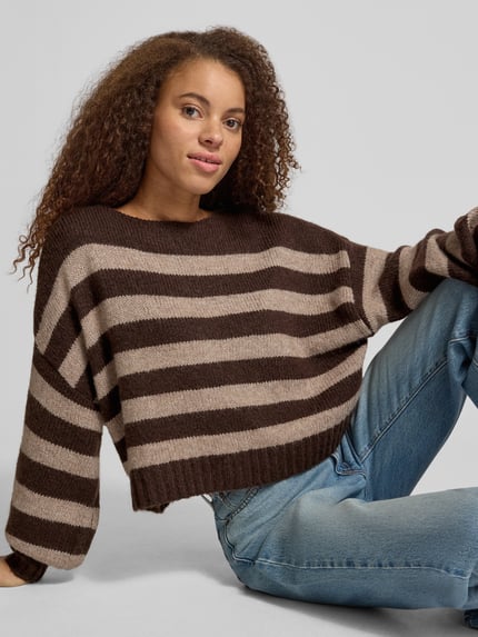 Frauenmodel trägt Pullover mit U-Boot-Ausschnitt von ONLY in mehrfarbiger Strickoptik mit Streifen, gerippte Abschlüsse, Nahaufnahme Oberkörper.