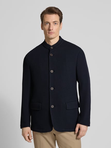 Männermodel trägt Slim Fit Sakko mit Stehkragen und Pattentaschen von Emporio Armani, dunkelblauer Material-Mix mit Viskose-Anteil, Knopfleiste, strukturierte Oberfläche, Ganzkörperansicht von vorne.