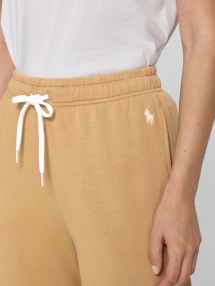 Vrouwenmodel draagt Regular Fit Sweathose uit katoenmix van Polo Ralph Lauren in lichtbruin met wit logo, detailopname heup.