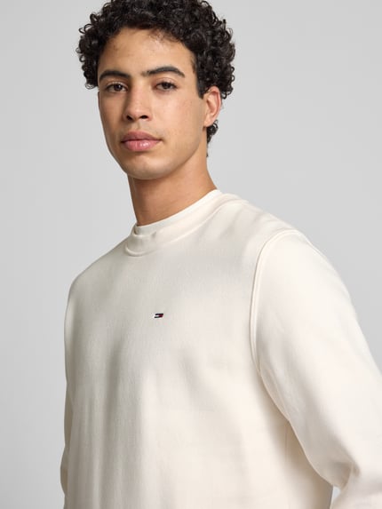 Männermodel trägt Regular Fit Sweatshirt aus Baumwoll-Mix von Tommy Jeans, Optik: Unifarben, Logo-Stitching, Nahaufnahme Oberkörper.