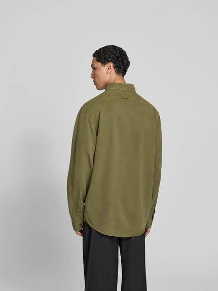 Męski model nosi Freizeithemd aus reinem Lyocell od Filippa K, kolor oliwkowy, krój relaxed fit, długi rękaw, materiał gładki, widok całej sylwetki z tyłu. Długość pleców w rozmiarze 50: 72 cm, szerokość ramion w rozmiarze 50: 48 cm, długość rękawa w rozmiarze 50: 70 cm, kieszeń na piersi i kołnierzyk button-down.