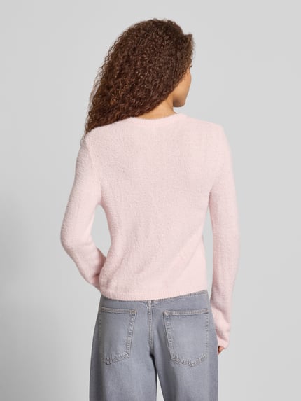 Frauenmodel trägt Strickjacke mit Herzknöpfen von ONLY in zartem Rosa zu hellblauer Denim, Ganzkörperansicht Rückansicht. Damen Strickjacke von ONLY.