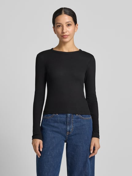 Frauenmodel trägt schwarzes Slim Fit Langarmshirt aus Baumwoll-Mix Modell 'CHLOE' von VERO MODA, kombiniert mit blauer Jeans, Ganzkörperansicht von vorne. Damen Langarmshirt von VERO MODA.