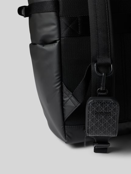 Produktfoto, Rolltop-Rucksack mit Label-Patch von CK Calvin Klein in Schwarz mit Seitenfächern, verstellbaren Schulterriemen, Detailaufnahme