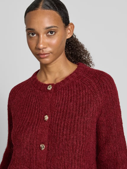 Frauenmodel trägt Regular Fit Cardigan in Strick-Optik von Christian Berg Woman Selection in dunkelrot, Knopfleiste, Nahaufnahme Oberkörper.