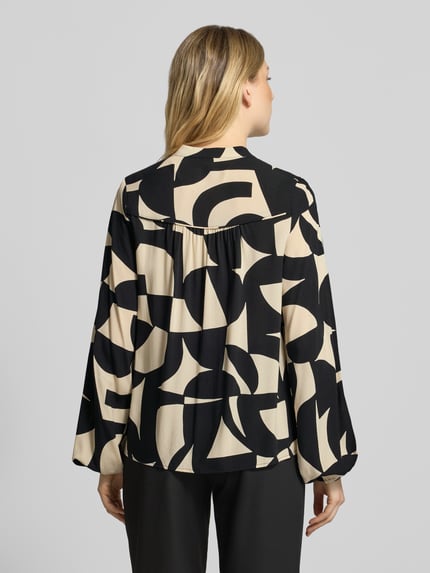 Frauenmodel trägt Langarmbluse mit verdeckter Knopfleiste von SOYACONCEPT, abstraktes, grafisches Allover-Muster in Beige und Schwarz, Webware, Stehkragen, Manschetten, Ganzkörperansicht Rückansicht.