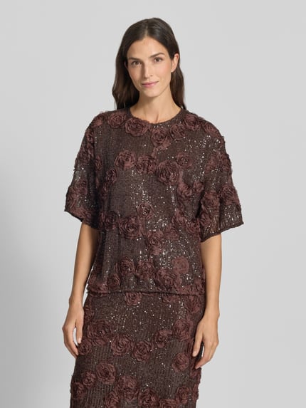 Frauenmodel trägt Blusenshirt mit Pailletten Modell 'ELYSIA' von YAS, Material-Mix, Relaxed Fit, Braun, Struktur, Nahaufnahme Oberkörper.