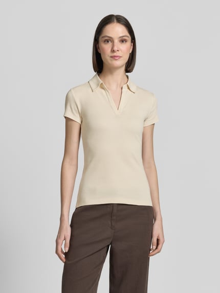 Vrouwenmodel draagt T-shirt met polokraag model 'Kleoh Polo' van Someday, mix van katoen en elastaan, slim fit, riblook, V-hals, ruglengte maat 36: 60 cm, lichte beige kleur, gladde textuur, rechte vormen, vooraanzicht bovenlichaam.