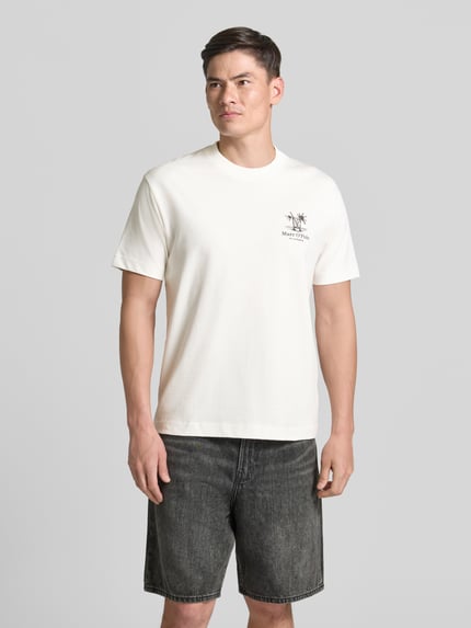 Männermodel trägt weißes Relaxed Fit T-Shirt aus reiner Baumwolle von Marc O'Polo, kombiniert mit dunkler Shorts, Herren T-Shirt, Ganzkörperansicht von vorne.