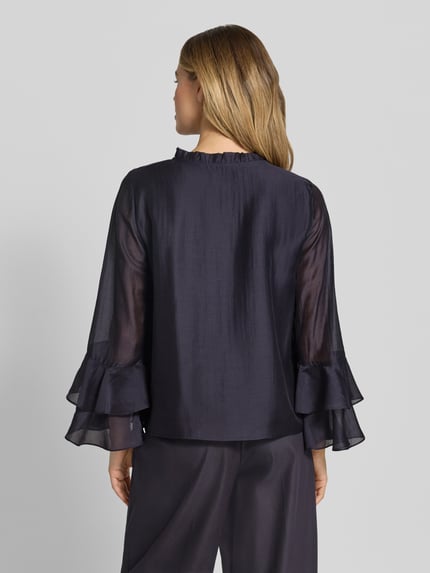 Frauenmodel trägt Regular Fit Bluse aus Lyocell-Mix mit Volants von Comma in dunklem Blau, transparente Ärmel, Rückenlänge 58 cm, Ganzkörperansicht Rückansicht.