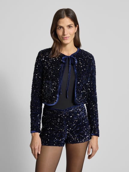 Frauenmodel trägt dunkelblauen, glitzernden Bolero mit Pailletten und Schnürung Modell 'XTURNER' von Mango, Nahaufnahme Oberkörper.