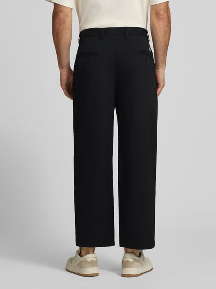 Männermodel trägt Loose Fit Weite Hose aus Baumwoll-Mix von Lacoste in Schwarz, glatte Oberfläche, Herren Weite Hose. Ganzkörperansicht Rückansicht.
