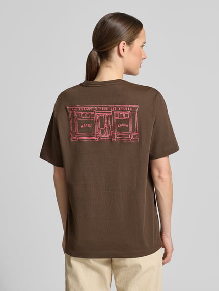 Frauenmodel trägt Damen T-Shirt aus reiner Baumwolle Modell 'BROOK SS HOTEL' von Selected Femme in Braun, Optik: Unifarben, Label-Stitching-Applikation, Relaxed-Fit, Rundhals, Kurzarm, Materialverarbeitung: Jersey, Ganzkörperansicht Rückansicht.