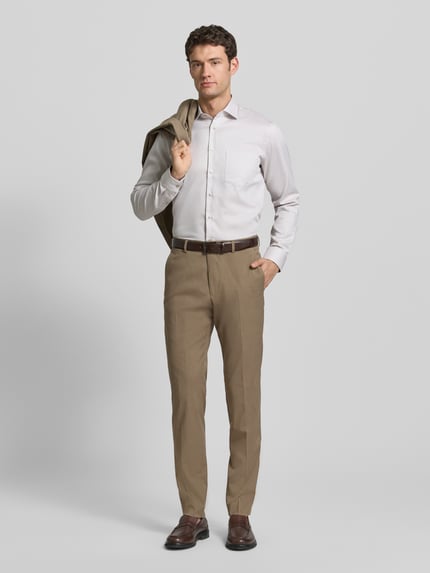 Männermodel trägt Regular Fit Anzughose mit Viskose-Anteil von s.Oliver BLACK LABEL in Optik: Unifarben, Melange, Materialverarbeitung: Chambray, mit Knopf-Reißverschluss, Label-Stitching, Gürtelschlaufen, Bügelfalten sowie seitlichen Eingrifftaschen und Gesäßtaschen, Ganzkörperansicht von vorne.