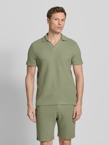 Männermodel trägt Regular Fit Poloshirt aus Baumwoll-Mix von MCNEAL in Olivgrün, Waffle-Piqueé, Umlegekragen, Kurzärmelig, Ganzkörperansicht von vorne.