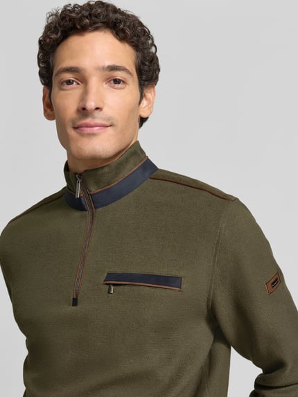 Männermodel trägt Sweatshirt mit Stehkragen und Reißverschluss von bugatti, Olivgrün, Brusttasche, Regular Fit, Nahaufnahme Oberkörper. Baumwoll-Mix, Label-Detail, KI-modifiziertes Bild.