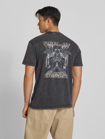 Męski model nosi Regular Fit T-Shirt aus reiner Baumwolle od Replay, z efektem melanżu, detal z logo, kolor czarny, Długość tyłu w rozmiarze M: 75 cm, Ganzkörperansicht Rückansicht.