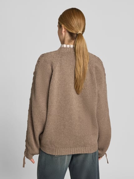 Modelka nosi Oversized Sweatshirt aus Woll-Mix von ROTATE, mieszanka wełny, krój oversized fit, imitacja dzianiny, pleciony detal, okrągły dekolt, długość tyłu w rozmiarze S: 65 cm, widok całej sylwetki z tyłu.